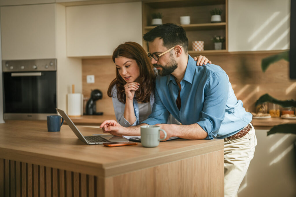 Couple managing home finances using laptop in modern kitchen