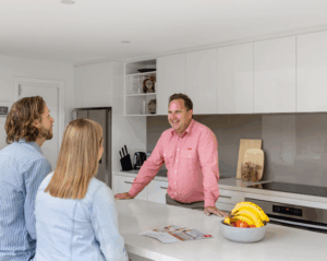 Real estate agent talking to couple in modern kitchen.