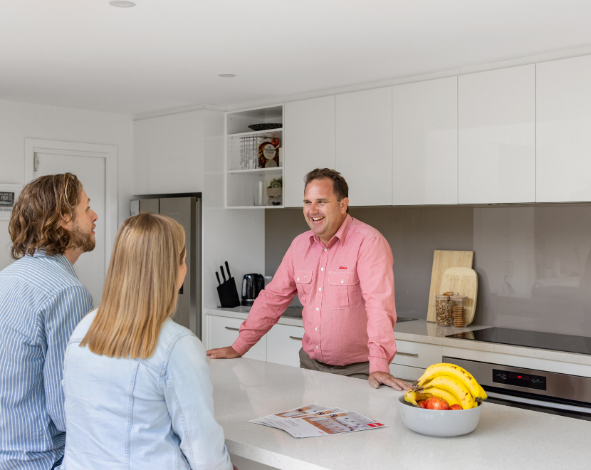 Real estate agent talking to couple in modern kitchen.