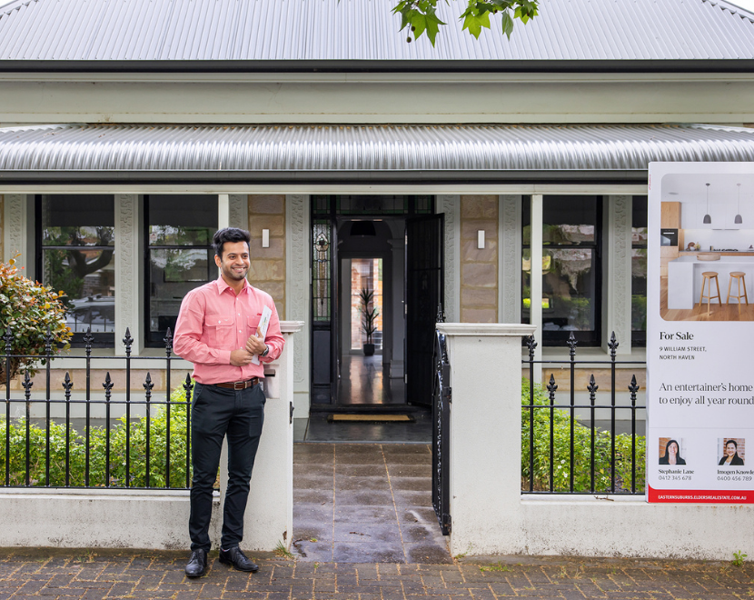 Real estate agent standing outside a property for sale in front of Elders Real Estate.